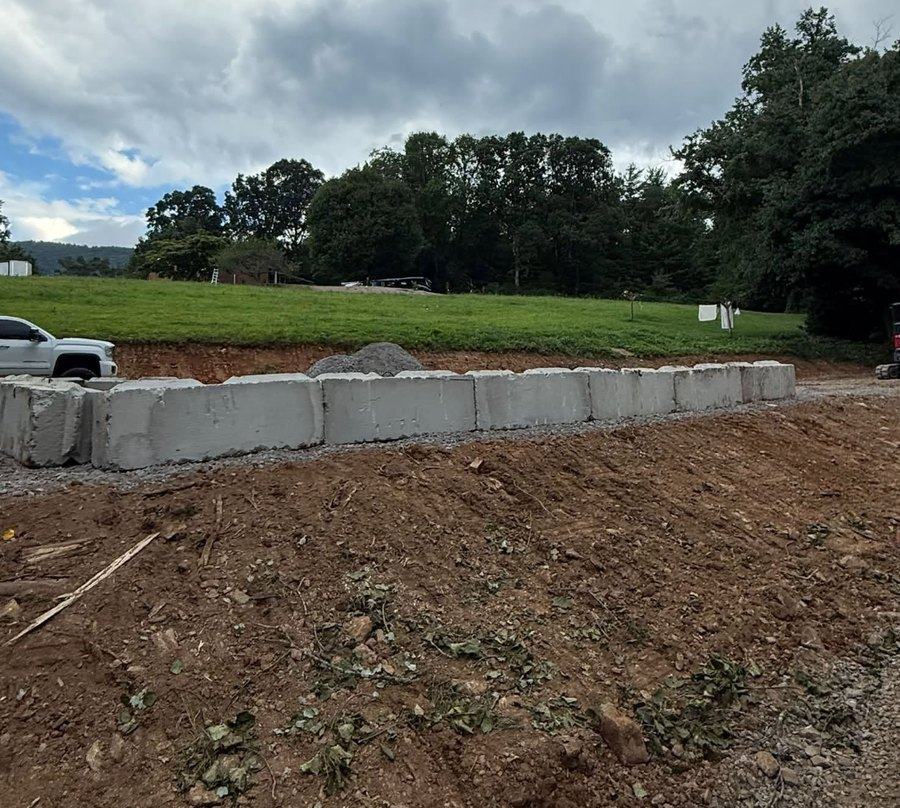 A block retaining wall under construction to hold a cut bank.