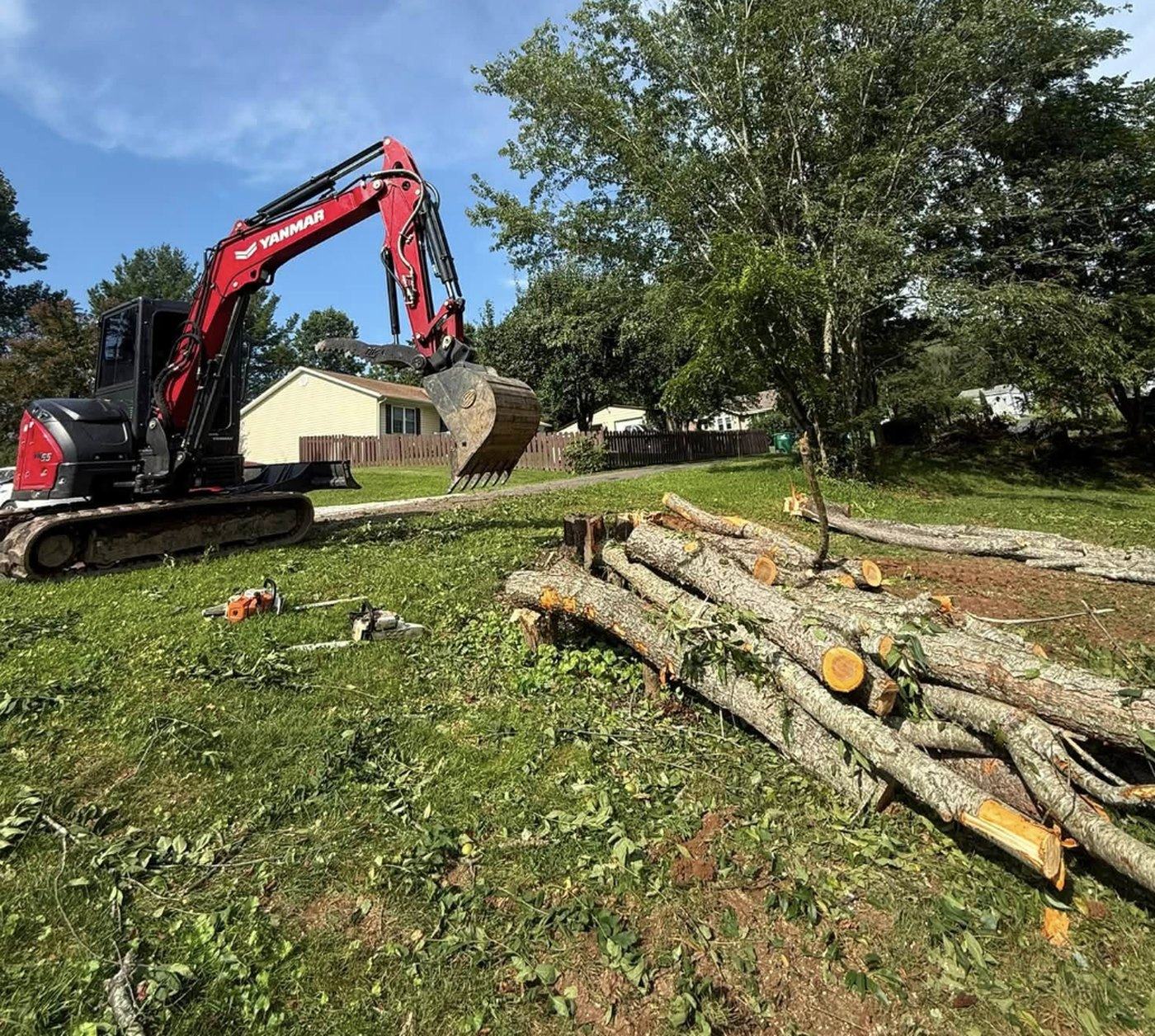 A tracked excavator handling felled timber during a land clearing job.