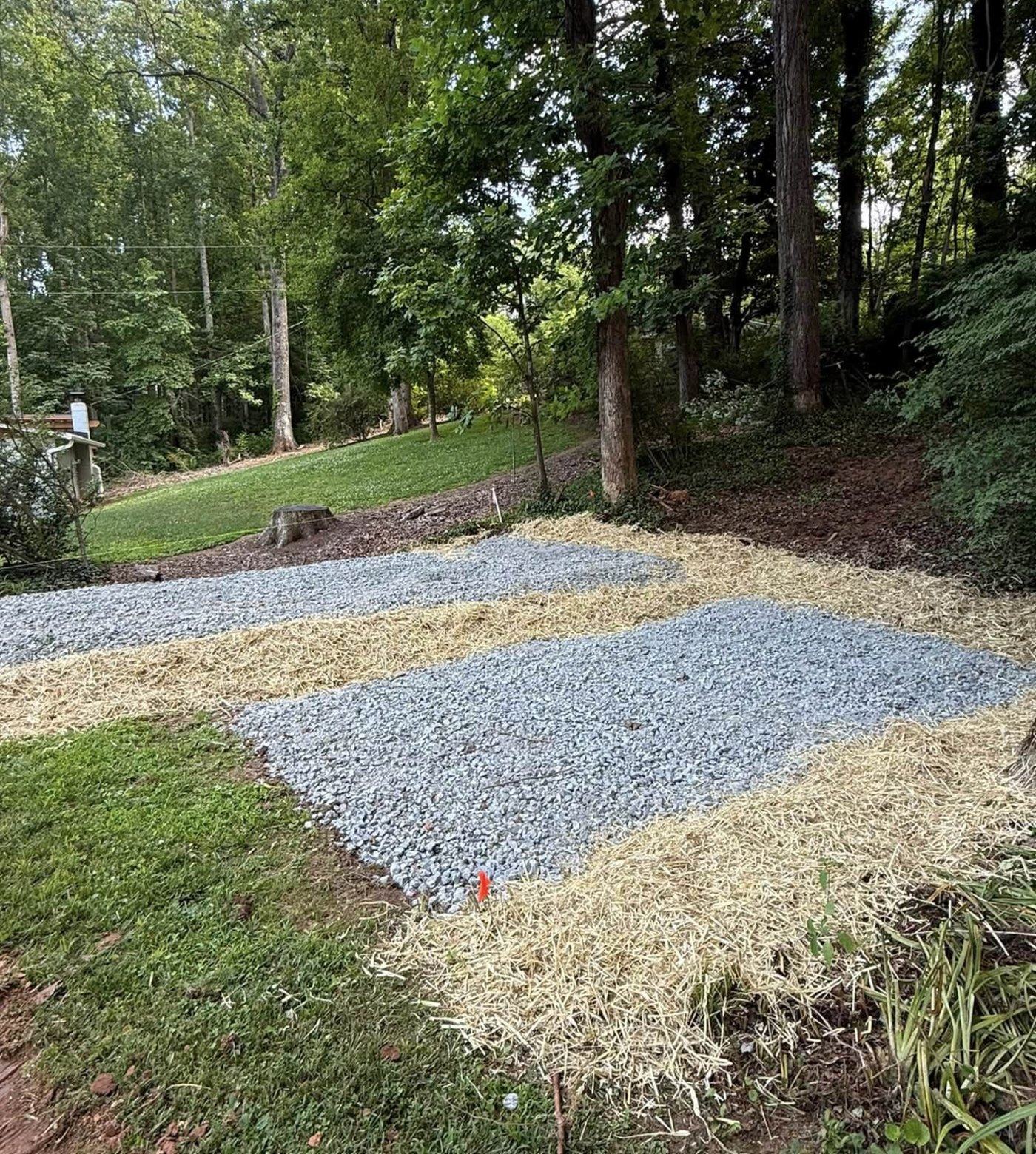 A new gravel driveway approach under mature trees, with fresh stone edging.
