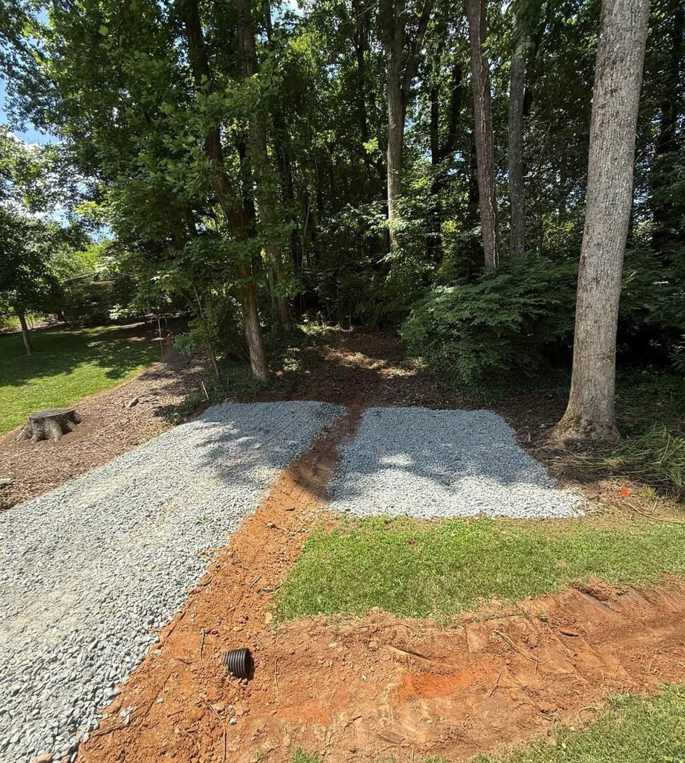 A gravel driveway turnaround built in a wooded lot.