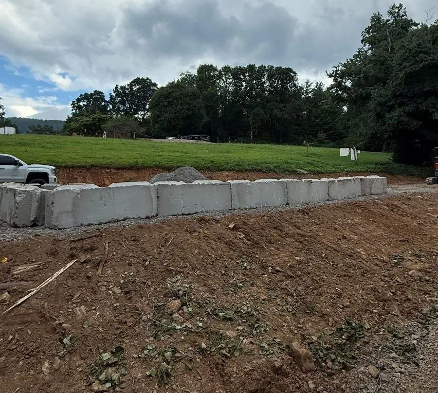 A block retaining wall under construction to hold a cut bank.