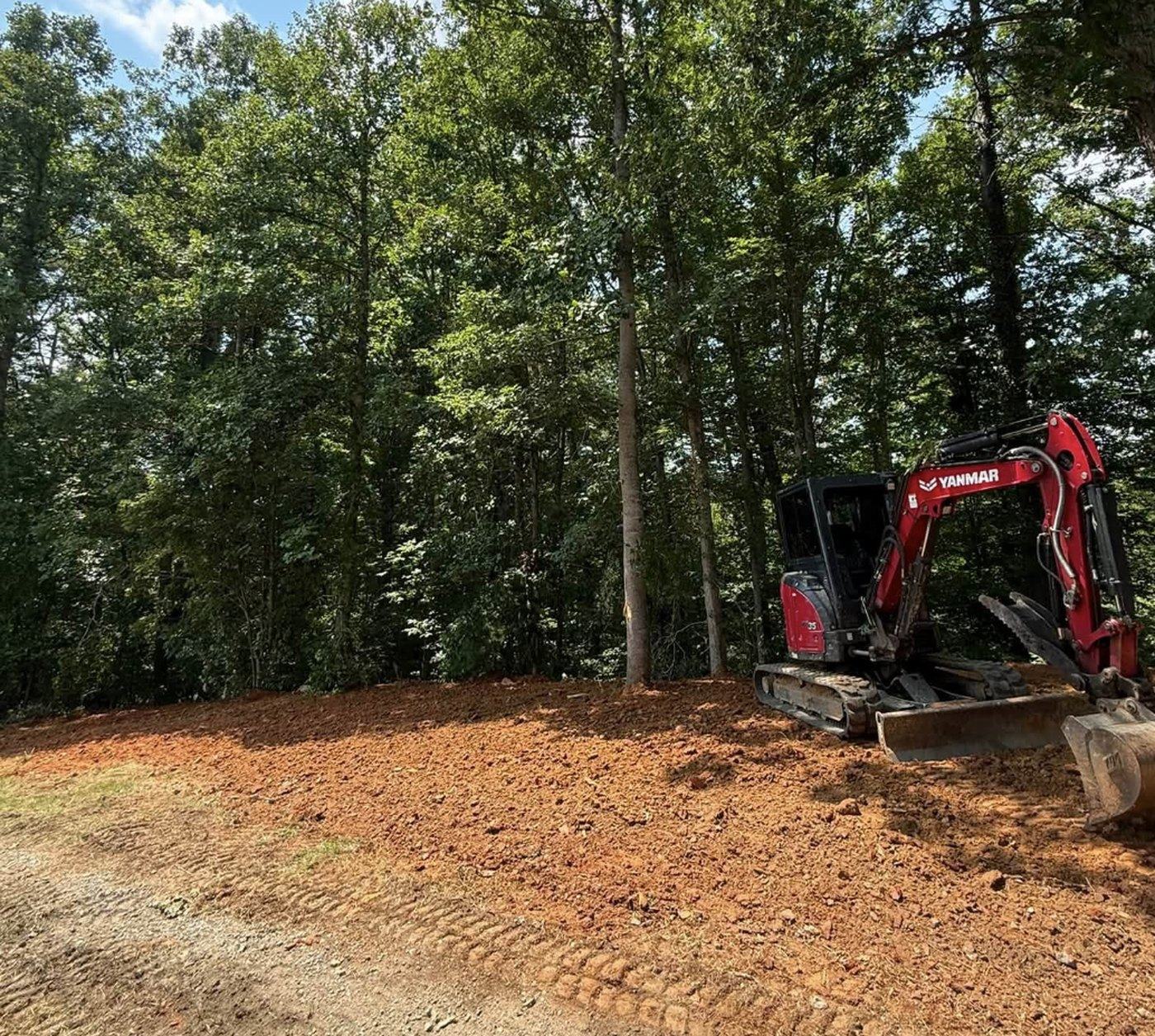 A mini excavator working a steep cut bank alongside a new driveway.