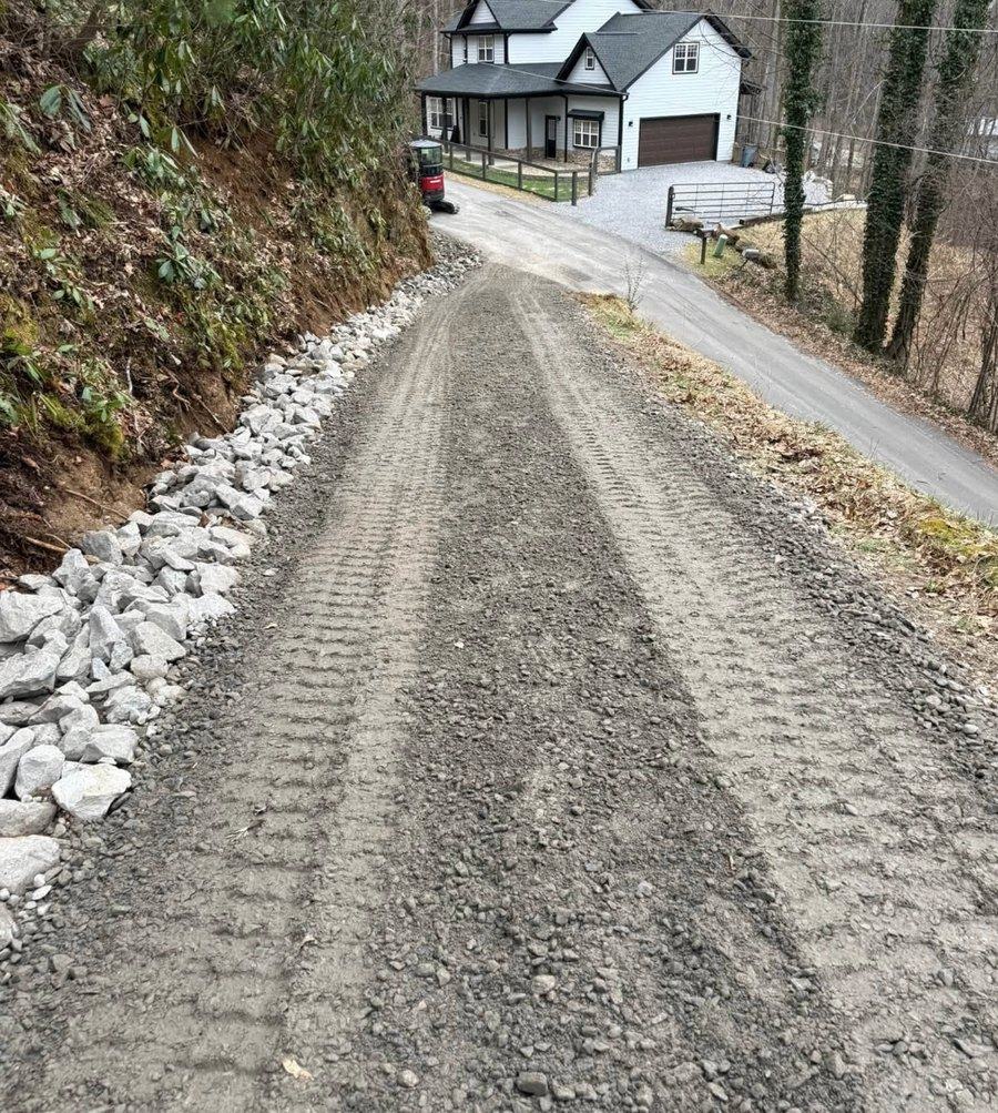 A steep gravel driveway rising to a house, edged with stone.